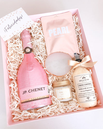 Esta Gift Box inspirada en mamá incluye:  • Vino espumoso rosado JP. Chenet  • Vela aromática White Lily • Crema corporal de Vainilla + Jalea Real con FPS 50 • Mascarilla facial Pearl • Joyero / Portavasos blanco • Caja Premium • Listón • Tarjeta de dedicatoria