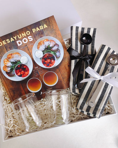 Esta Gift Box incluye:  • Libro con recetas para desayunos • Par de vasos de cristal doble fondo  • Par de servilletas de tela negra con blanco • Cuchara clip medidora negra • Cuchara clip medidora negra • Caja Premium • Listón • Tarjeta de dedicatoria